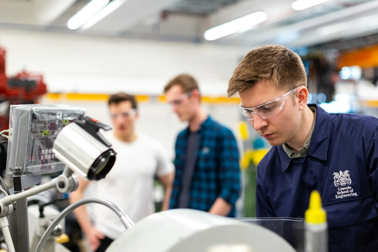 Engineer wearing safety glasses working beside industrial equipment